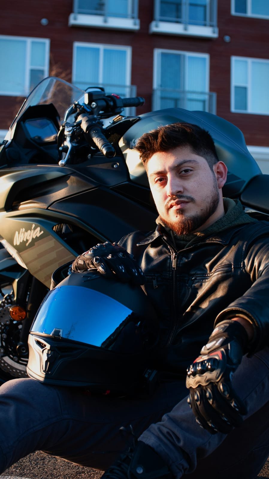 Golden-hour portrait of a rider seated beside a motorcycle